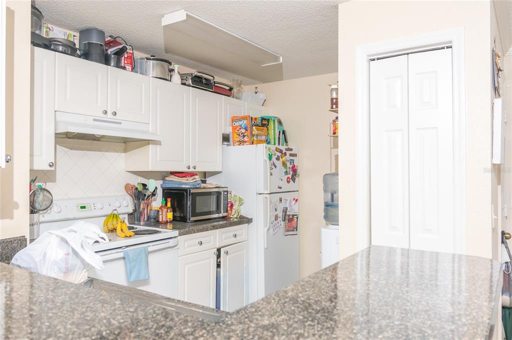 A kitchen features white cabinets, granite countertops, a white stove, and a refrigerator — 18001 RICHMOND PLACE DRIVE UNIT 735, TAMPA, FL