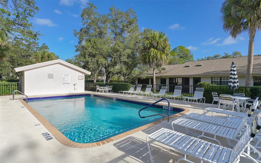 A rectangular swimming pool with lounge chairs on a concrete deck near a building — 5456 HAMPSTEAD HEATH UNIT 20, SARASOTA, FL