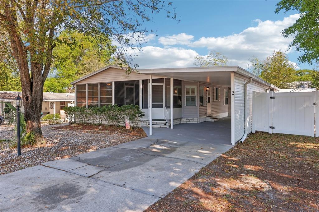 A single-story manufactured home with a screened porch, carport, and white vinyl privacy fence — 39 MAPLEHURST AVENUE, DEBARY, FL