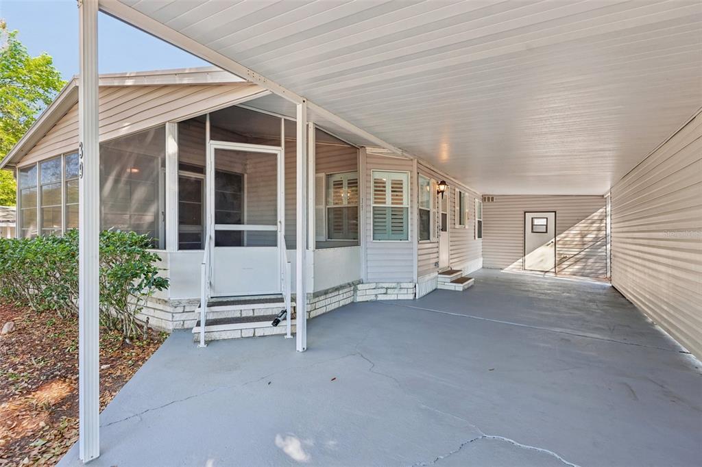 A light-colored mobile home exterior features a screened-in porch and a large, covered concrete carport — 39 MAPLEHURST AVENUE, DEBARY, FL