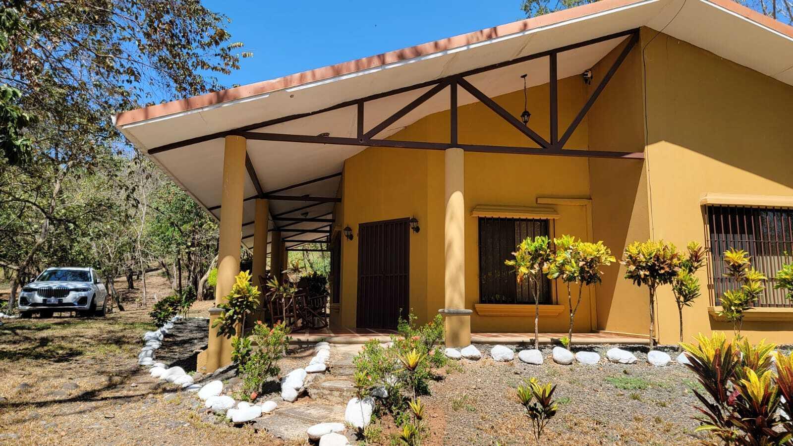 A yellow house with a covered porch, brown metal trusses, and a white gravel border — De Estación Bomberos 1km Norte 3km Al Oeste, FL
