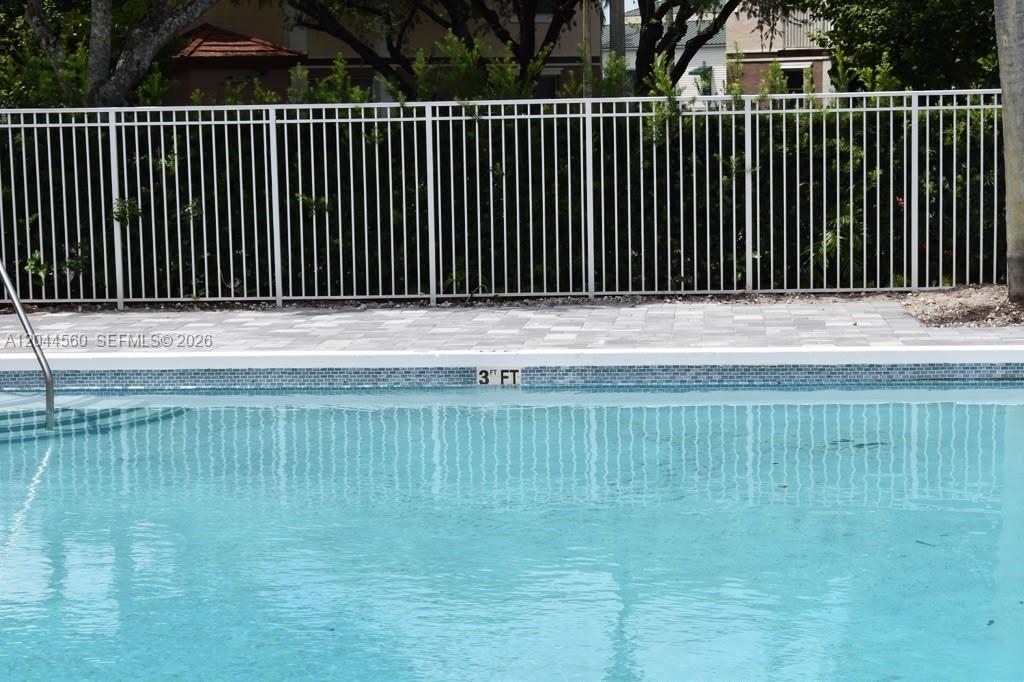 A swimming pool with a depth marker and a white metal fence in the background — PEMBROKE PINES, FL