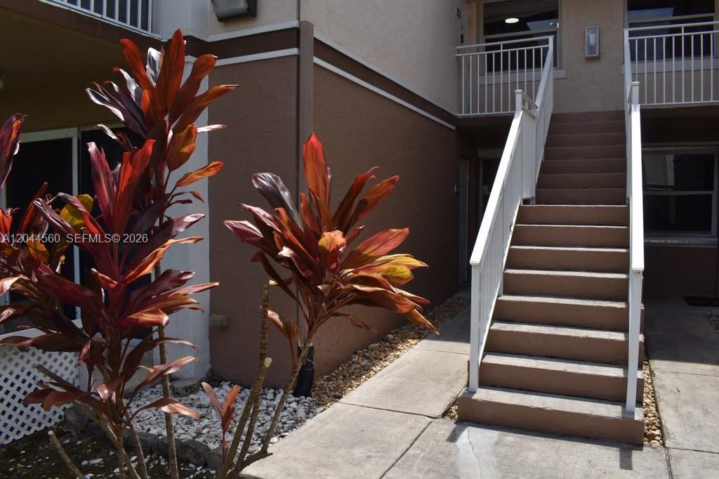 An exterior view shows a concrete staircase leading to an upper-level apartment balcony — PEMBROKE PINES, FL