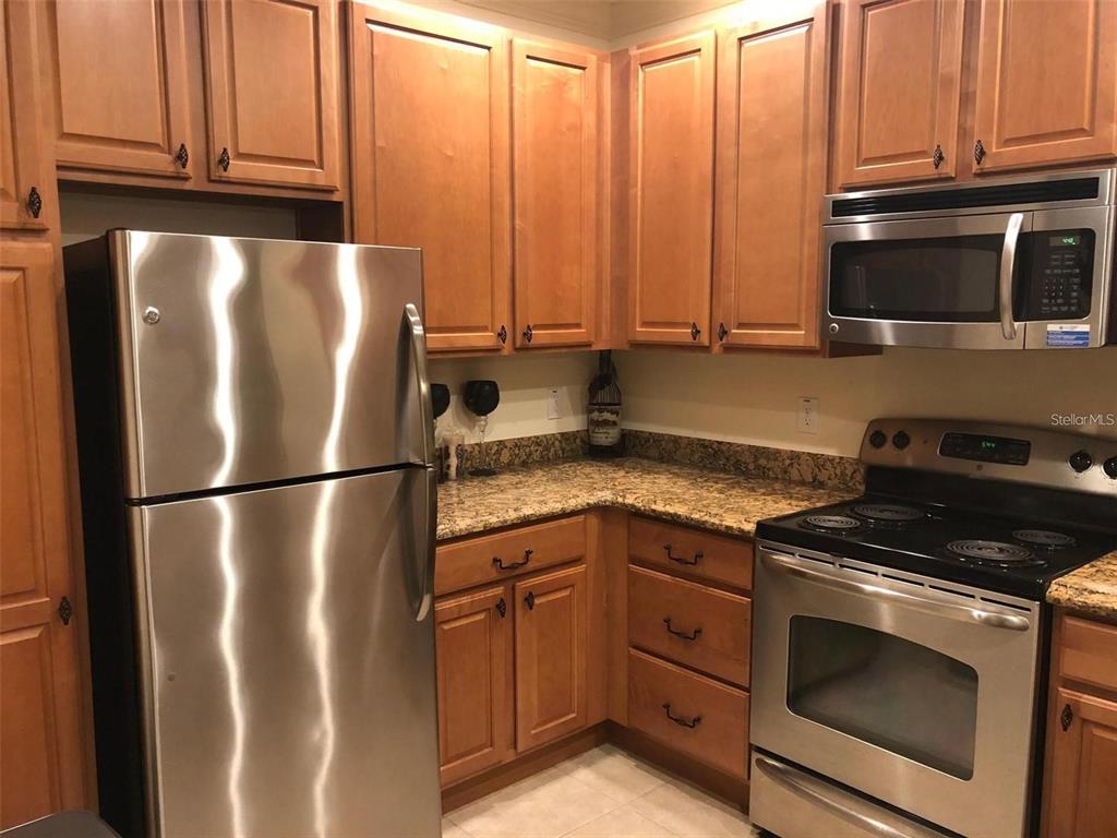 A kitchen features wood cabinets, granite countertops, and stainless steel appliances — 2846 BELLA VISTA DRIVE, DAVENPORT, FL