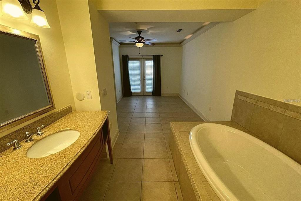 A bathroom features a granite vanity, a soaking tub, and a doorway leading to a room — 2846 BELLA VISTA DRIVE, DAVENPORT, FL