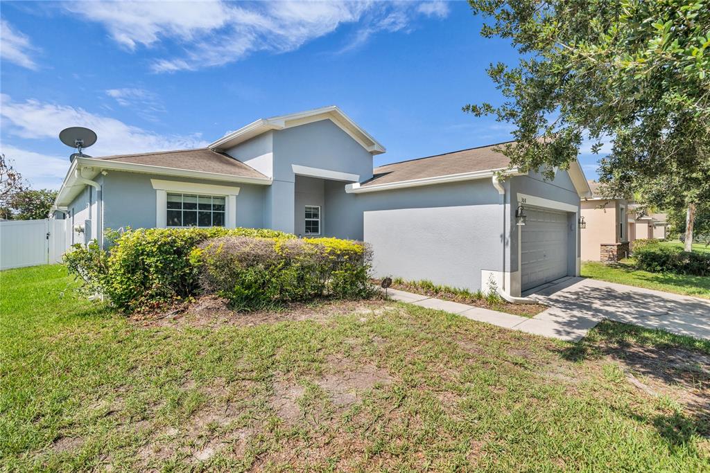 A single-story blue house with a two-car garage and a concrete walkway to the entrance — 308 BELLA ROSA CIRCLE, SANFORD, FL