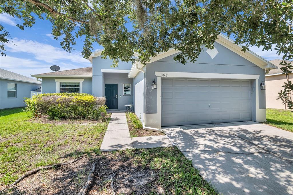 A single-story gray house with a two-car garage and a large tree in the yard — 308 BELLA ROSA CIRCLE, SANFORD, FL