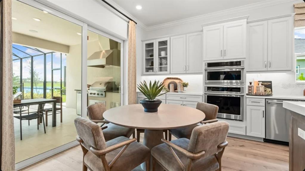 A kitchen with white cabinets, stainless steel appliances, and a round dining table near sliders — 26128 ASPARANO AVENUE, ENGLEWOOD, FL