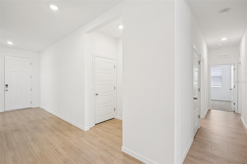 A bright hallway features light wood-look flooring, white walls, and several interior doors — 4665 BARBERRY AVENUE, LAKELAND, FL