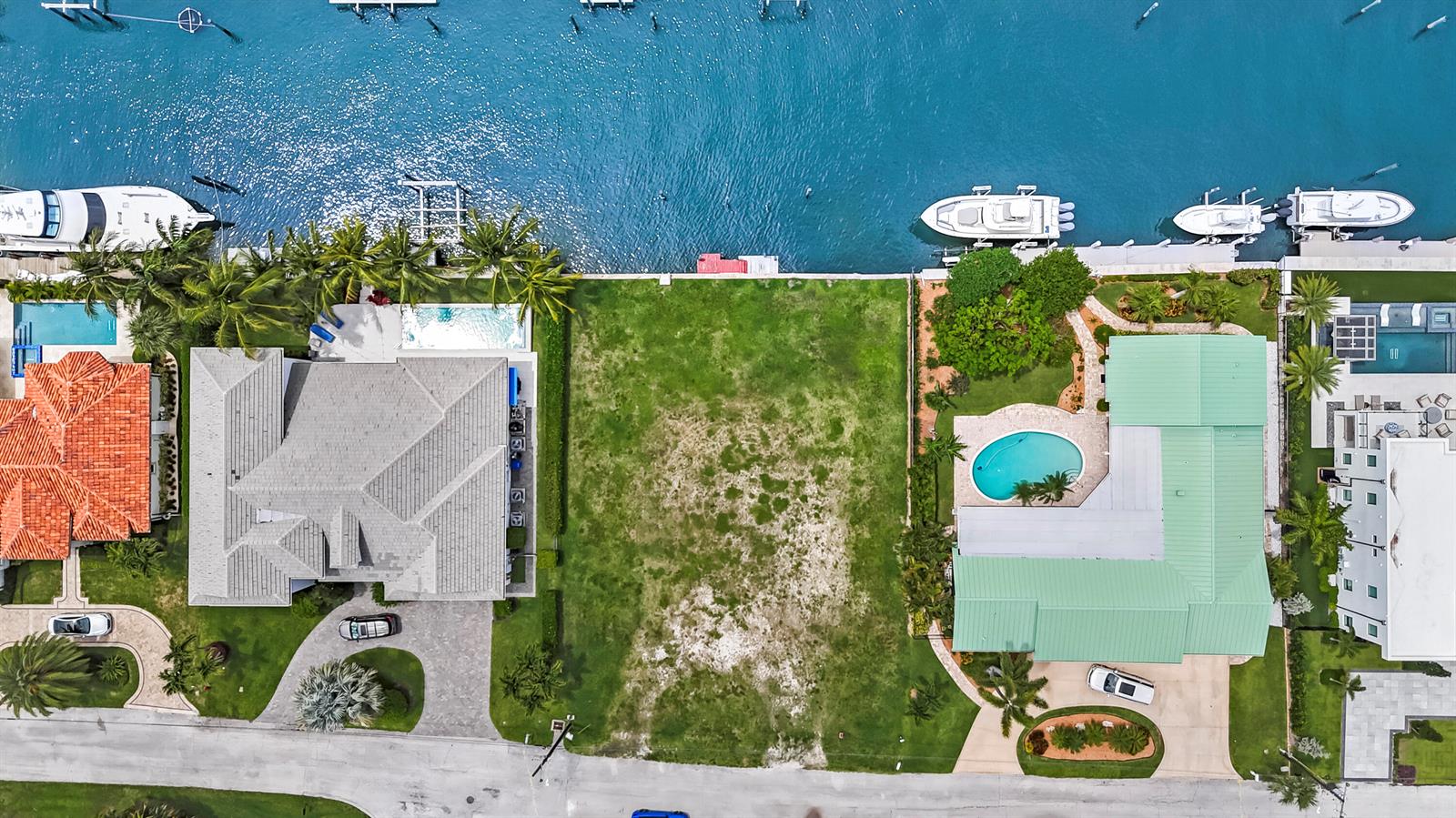 An aerial view shows a vacant waterfront lot situated between two residential properties with pools — 1121 Coral Way, Singer Island FL 33404, SINGER ISLAND, FL