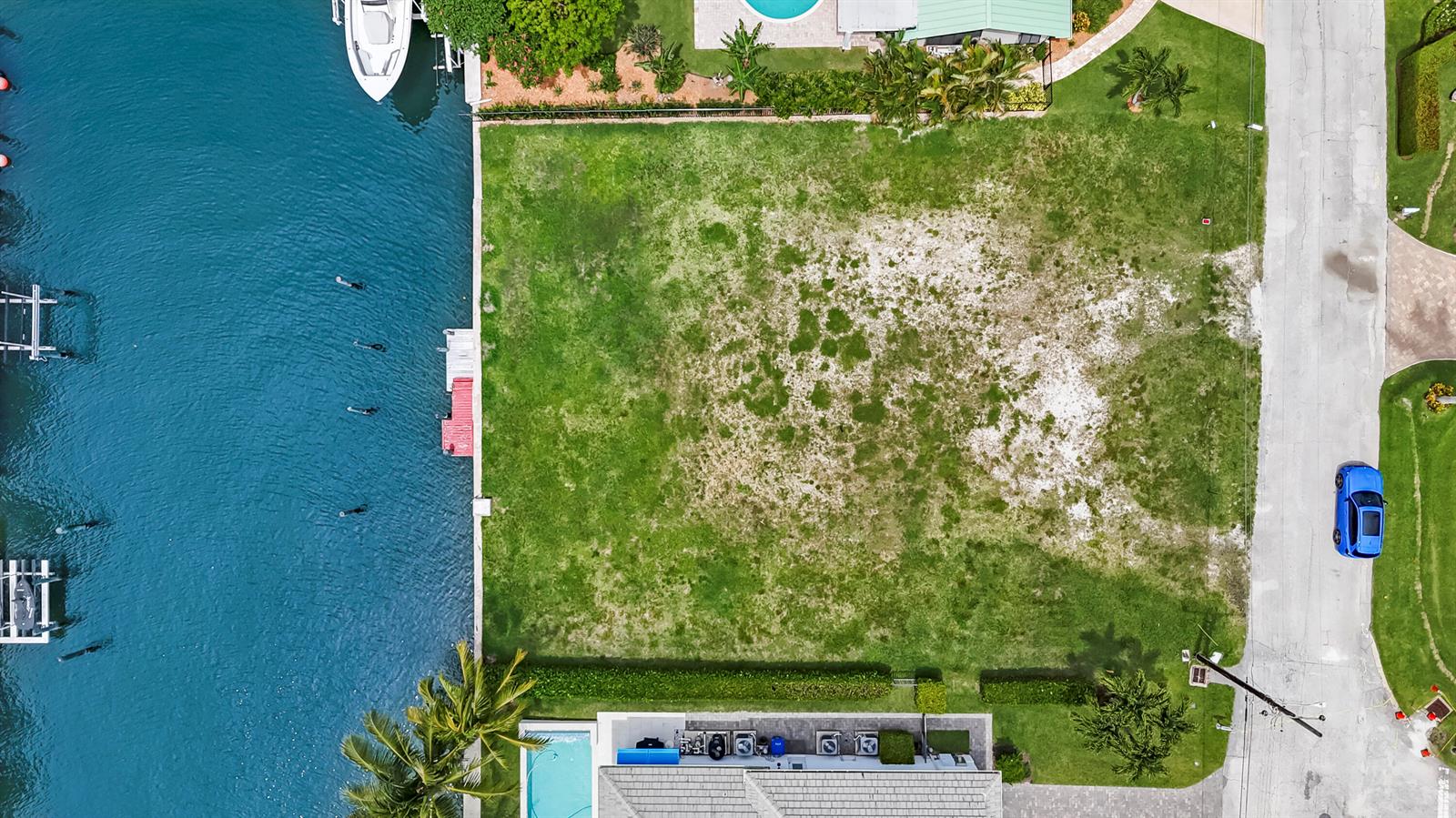An aerial view shows a vacant waterfront lot situated between a canal and a road — 1121 Coral Way, Singer Island FL 33404, SINGER ISLAND, FL