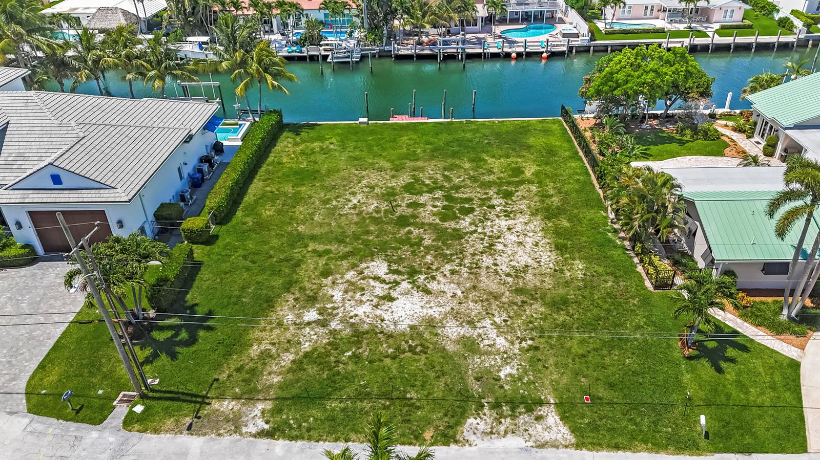 An aerial view shows a vacant waterfront lot situated between two residential houses — 1121 Coral Way, Singer Island FL 33404, SINGER ISLAND, FL