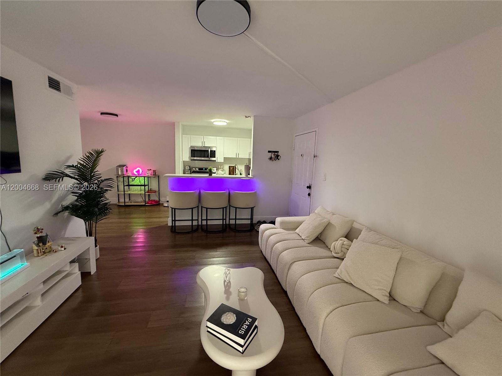 A living room features a white sofa, a coffee table, and a kitchen bar area — 7155 NW 179th St # 107, Hialeah FL 33015, HIALEAH, FL