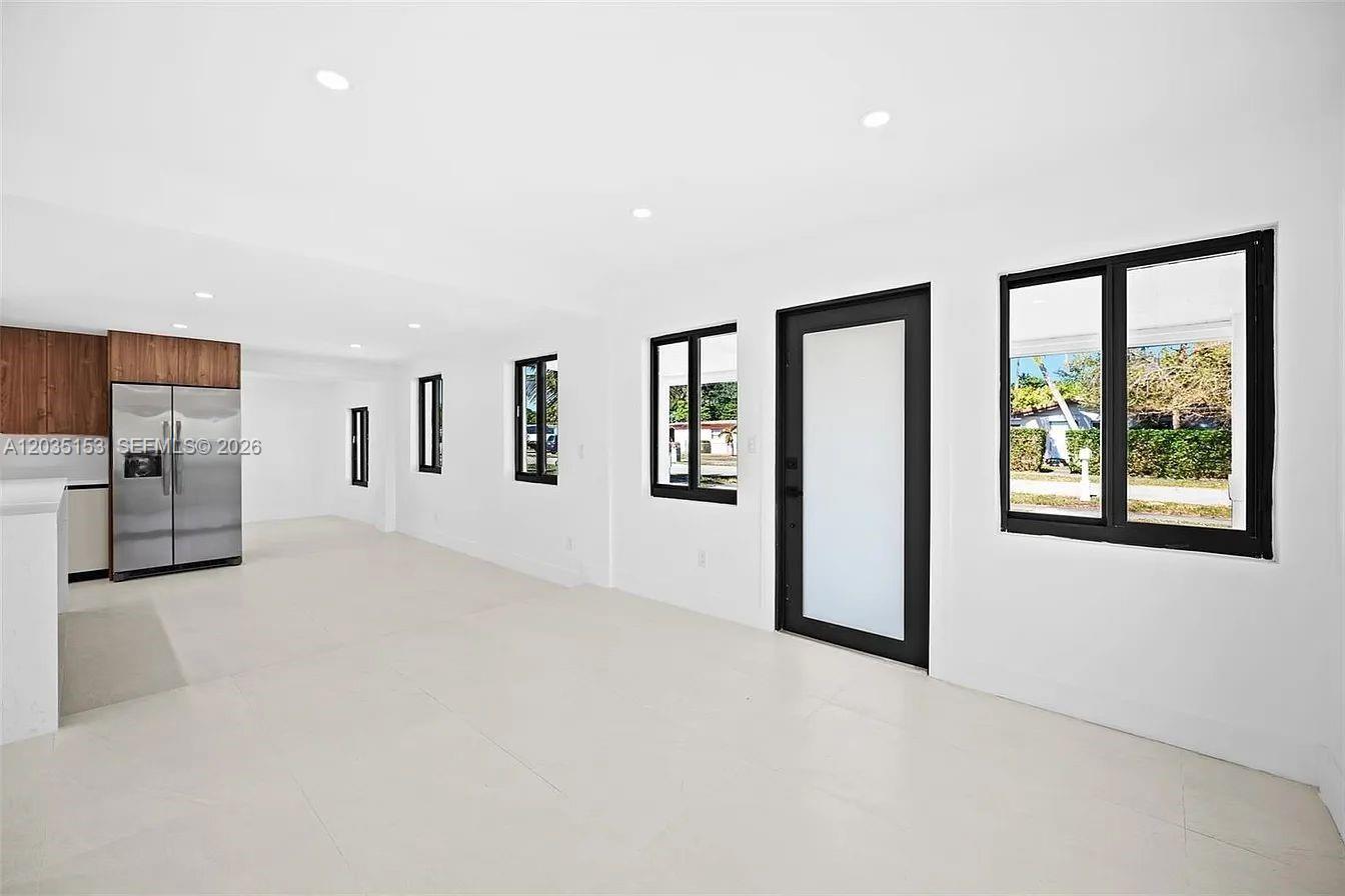 A minimalist room features white walls, tile flooring, a stainless refrigerator, and black-framed windows — 10000 SW 43rd St, Miami FL 33165, MIAMI, FL