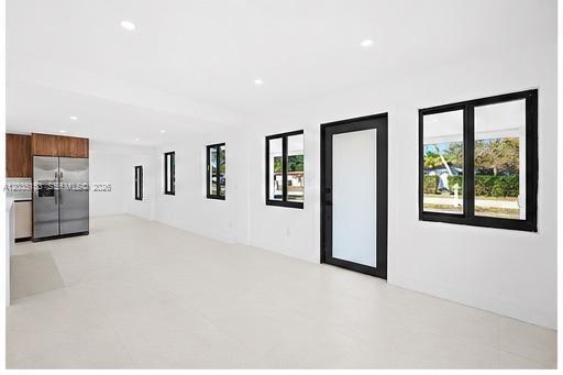 A bright, open-concept living area features white walls, tile floors, and a modern kitchen — 10000 SW 43rd St, Miami FL 33165, MIAMI, FL