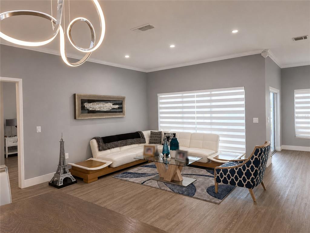 A living room features a white sectional sofa, a patterned armchair, and a modern chandelier — 3402 GREAT POND DRIVE, KISSIMMEE, FL