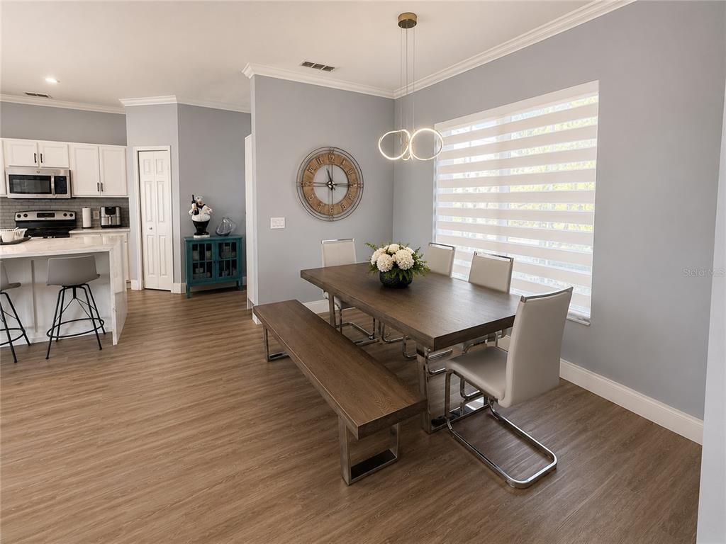 A dining area features a wooden table with a bench and chairs near a kitchen — 3402 GREAT POND DRIVE, KISSIMMEE, FL