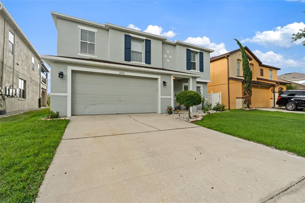 A two-story gray house with a two-car garage and blue shutters under a blue sky — 2730 AMANDA KAY WAY, KISSIMMEE, FL