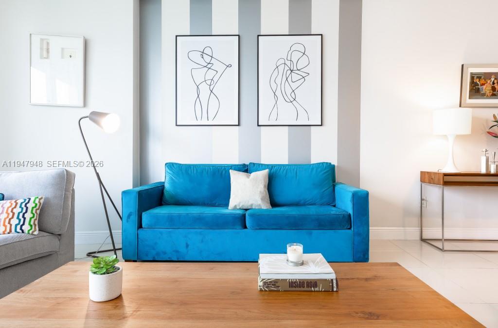 A living room features a blue velvet sofa, striped wall, and a wooden coffee table — 485 Brickell Ave # 4307, Miami FL 33131, MIAMI, FL