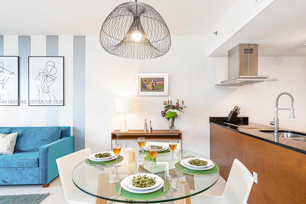 A dining area features a glass table, modern pendant light, and an adjacent kitchen — 485 Brickell Ave # 4307, Miami FL 33131, MIAMI, FL