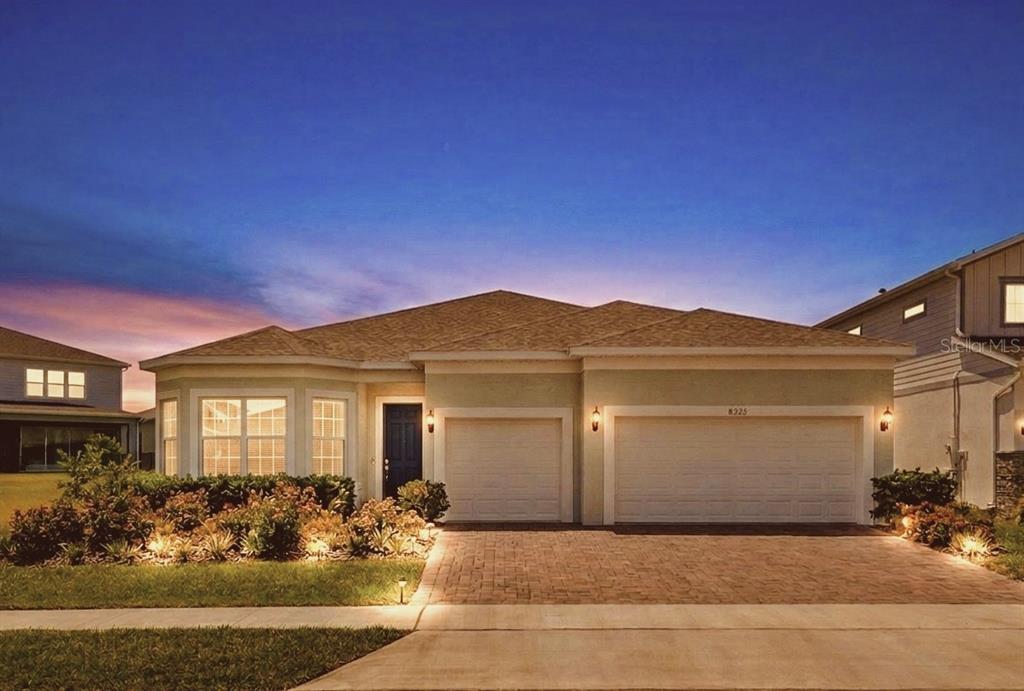 A single-story house with a three-car garage and a paved driveway at dusk — 8322 PARK CLIFF WAY, ORLANDO, FL