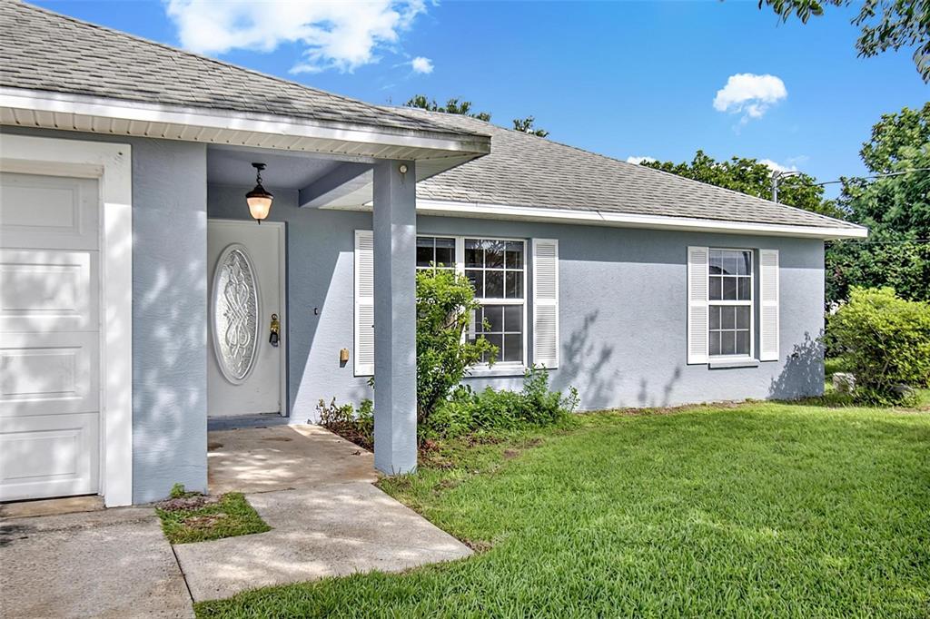 A light blue single-story house features a white front door, garage, and a grassy lawn — 9 LYTTON LANE, PALM COAST, FL