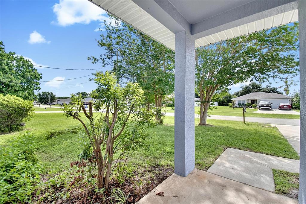 A view from a covered porch looking out onto a grassy front yard and street — 9 LYTTON LANE, PALM COAST, FL