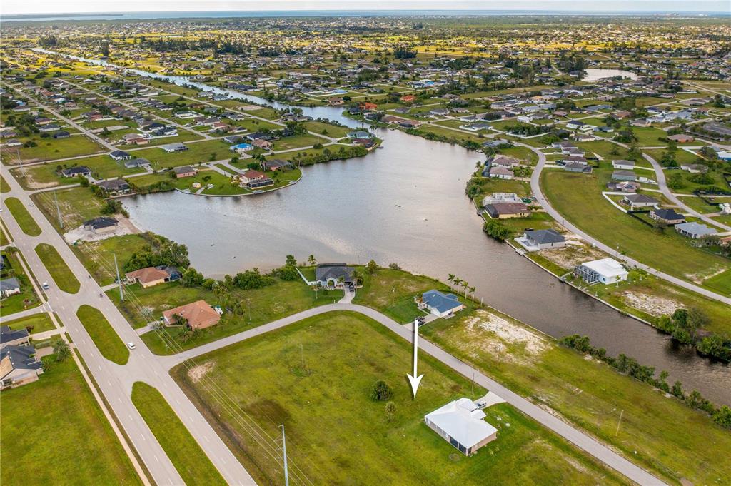 An aerial view shows a white house on a grassy lot near a canal — 1718 NW 8TH TERRACE, CAPE CORAL, FL