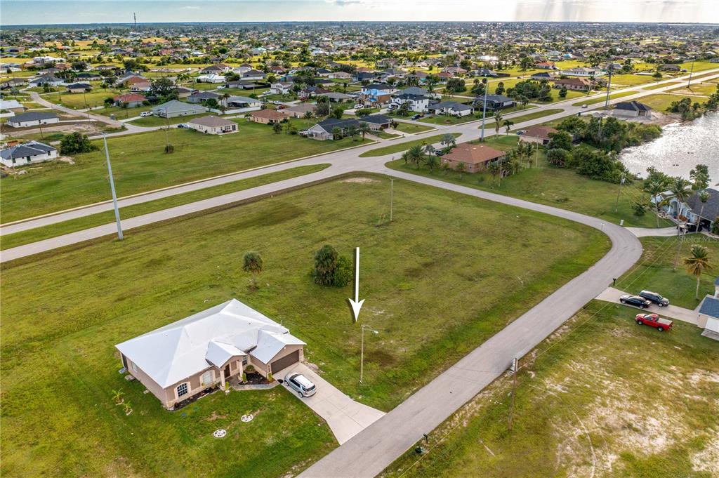 An aerial view shows a single-story house next to a large, vacant grassy lot — 1718 NW 8TH TERRACE, CAPE CORAL, FL