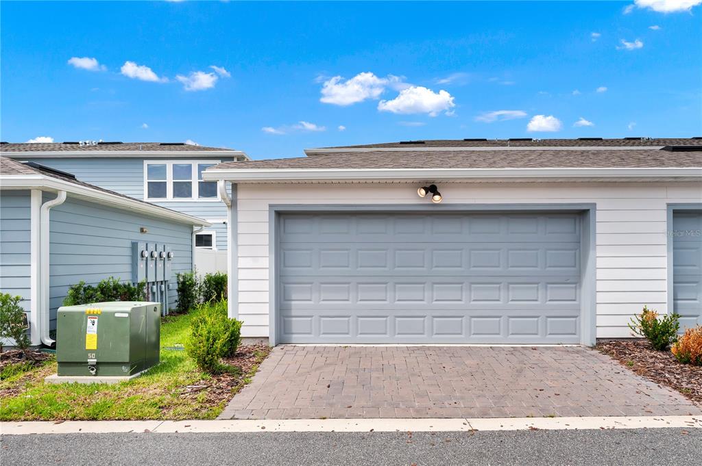 A gray garage door is set into a white-sided building with a paved driveway — 14253 LANIKAI BEACH DRIVE, ORLANDO, FL