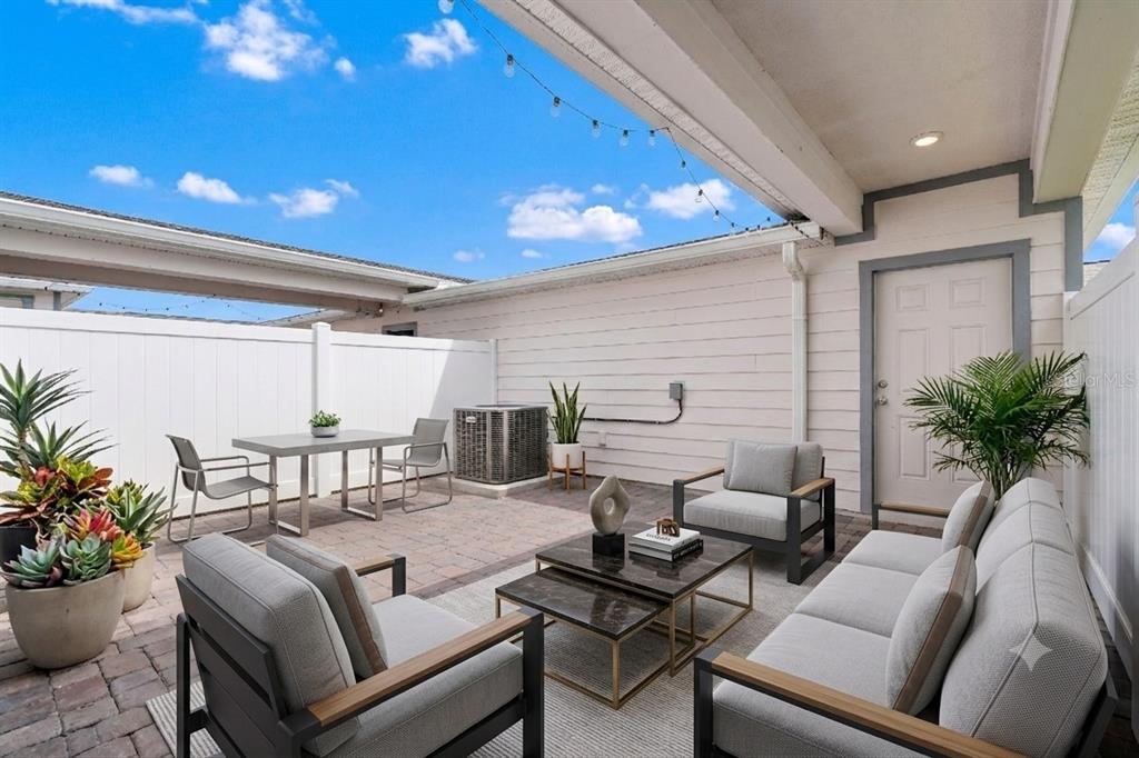 A paved outdoor patio features a dining set, lounge furniture, and a white privacy fence — 14253 LANIKAI BEACH DRIVE, ORLANDO, FL