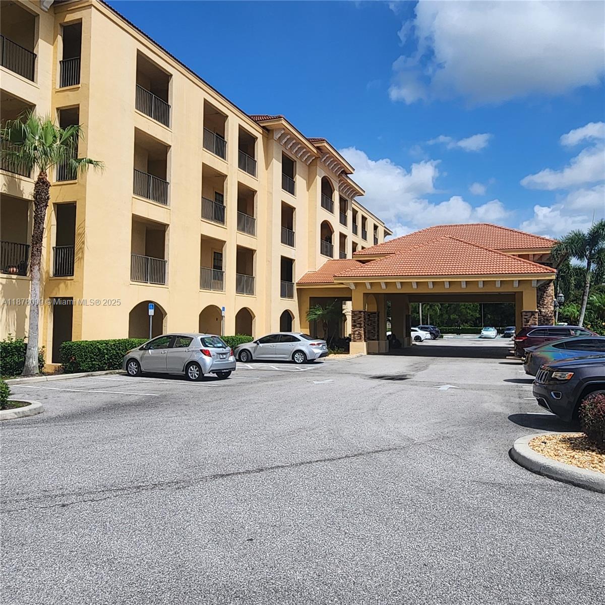A multi-story yellow apartment building features a covered entrance and a paved parking lot — 2351 Lakeview Dr # 114, Sebring FL 33875, SEBRING, FL