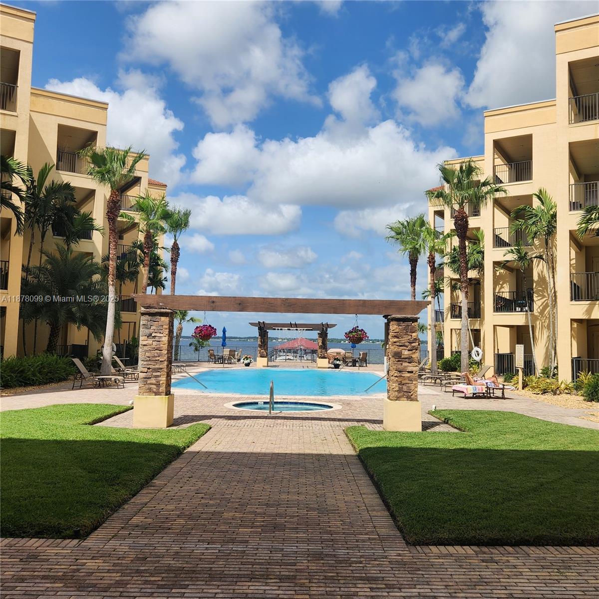 A swimming pool and hot tub are situated between two apartment buildings overlooking a lake — 2351 Lakeview Dr # 114, Sebring FL 33875, SEBRING, FL