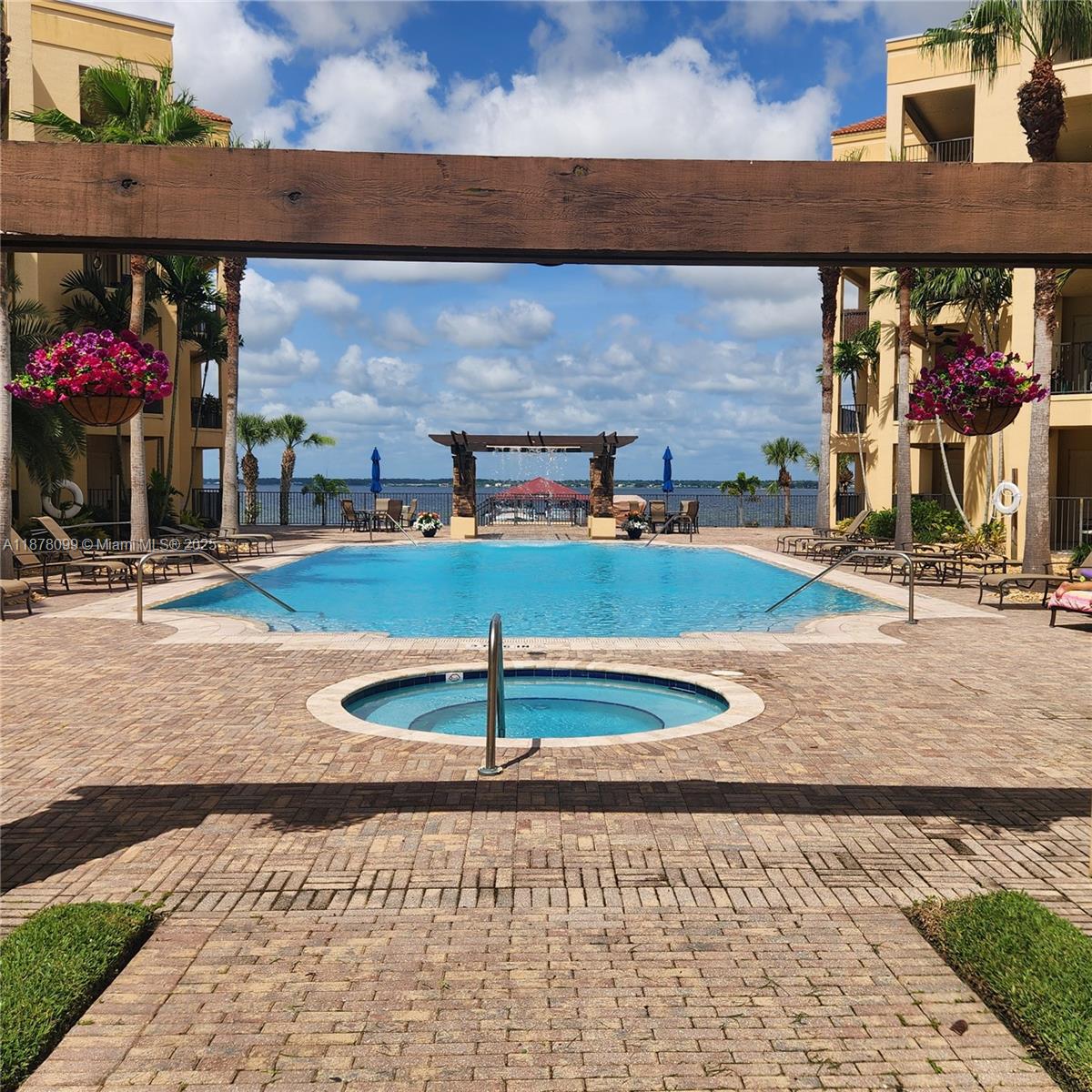 A swimming pool and hot tub are situated between two apartment buildings overlooking a lake — 2351 Lakeview Dr # 114, Sebring FL 33875, SEBRING, FL