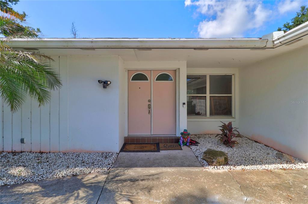 A front exterior view of a house featuring double pink doors and white siding — 54 LAKE LINK CIRCLE SE, WINTER HAVEN, FL