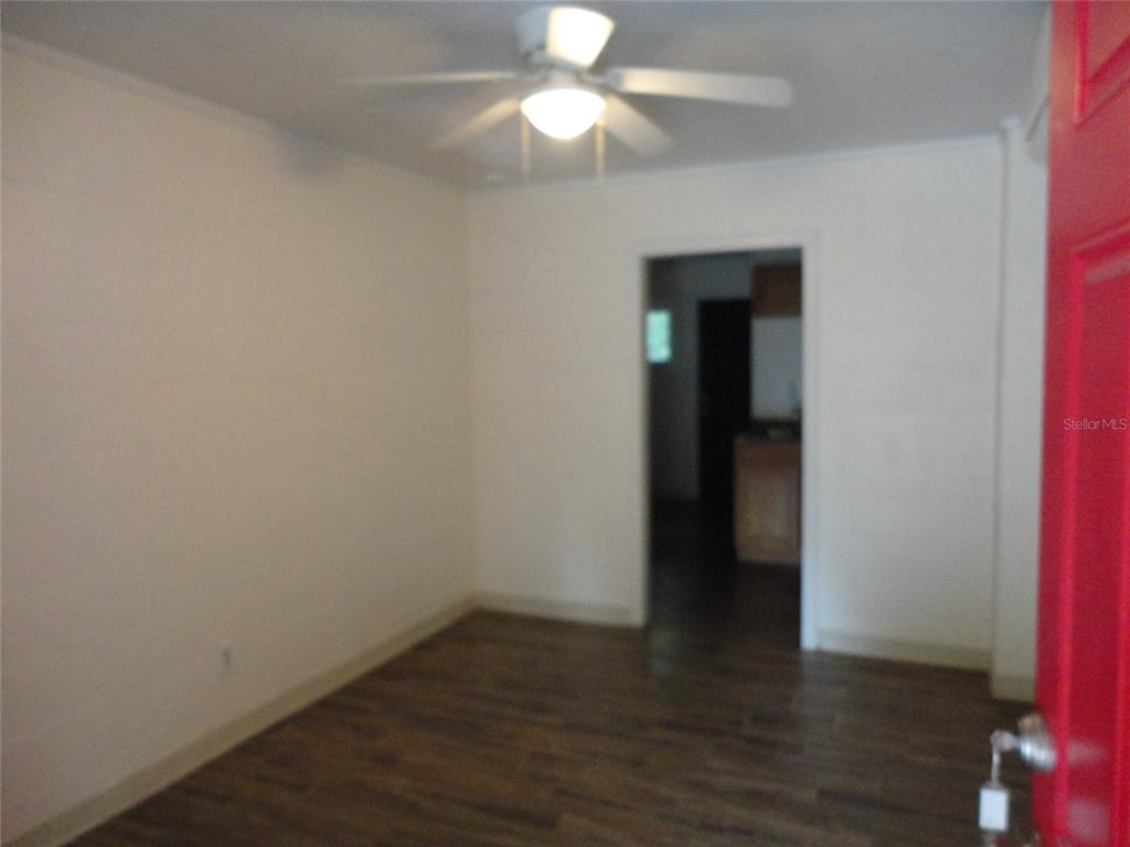 An empty room features wood-look flooring, white walls, and a ceiling fan — 1315 SE 3RD AVENUE, GAINESVILLE, FL
