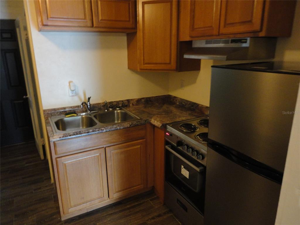 A small kitchen features wooden cabinets, a double sink, a stove, and a refrigerator — 1315 SE 3RD AVENUE, GAINESVILLE, FL