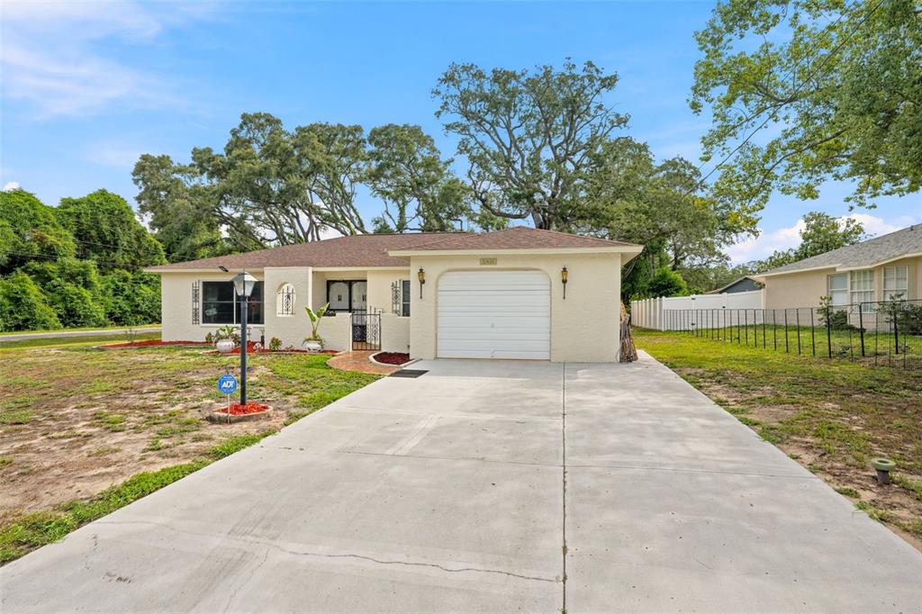 A single-story house with a beige stucco exterior, a one-car garage, and a concrete driveway — 5431 ALDERWOOD STREET, SPRING HILL, FL