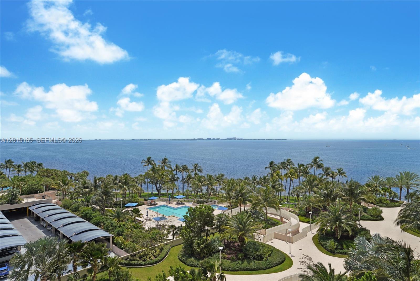 An elevated view shows a swimming pool, lush landscaping, and a parking structure near water — 1 Grove Isle Dr # A809, Miami FL 33133, MIAMI, FL