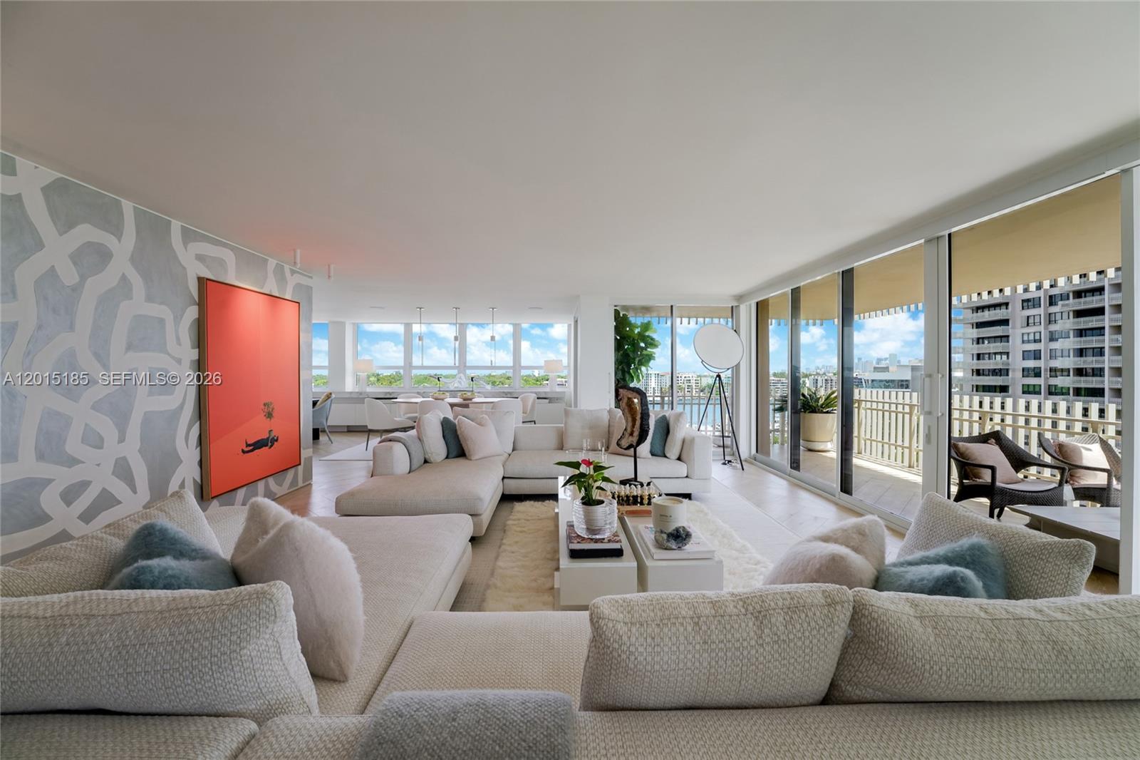 A spacious living room features a large sectional sofa, modern decor, and floor-to-ceiling balcony windows — 1 Grove Isle Dr # A809, Miami FL 33133, MIAMI, FL