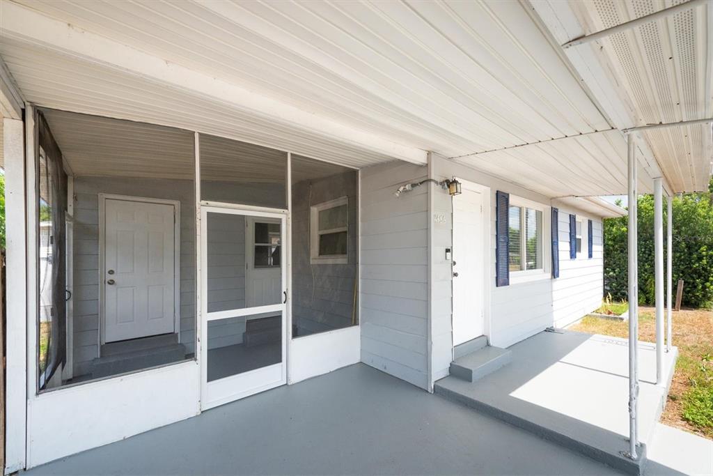 A covered porch with a screened-in section and two white doors on a gray house — 11456 106TH STREET, LARGO, FL