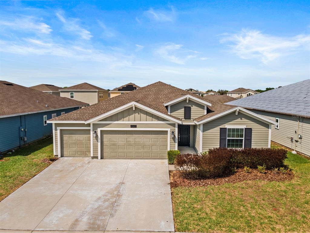 A single-story house with light green siding, a two-car garage, and a concrete driveway — 4327 LIGHTERKNOT TRACE, KISSIMMEE, FL