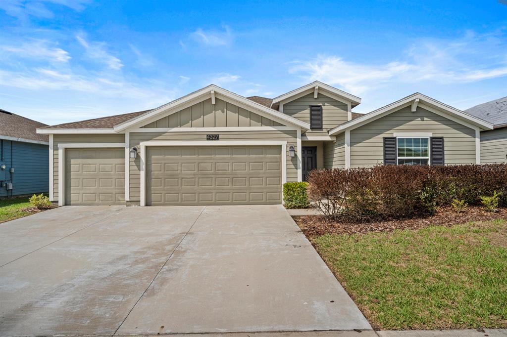 A single-story house with light green siding, a three-car garage, and a concrete driveway — 4327 LIGHTERKNOT TRACE, KISSIMMEE, FL