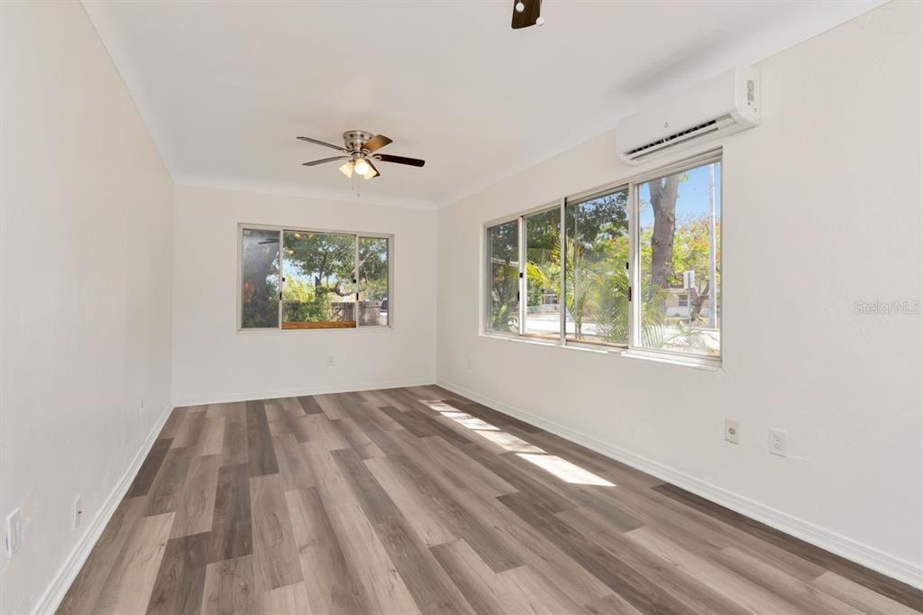 An empty room with light-colored walls, wood-look flooring, a ceiling fan, and a wall-mounted AC — 4939 HAINES ROAD N, ST PETERSBURG, FL