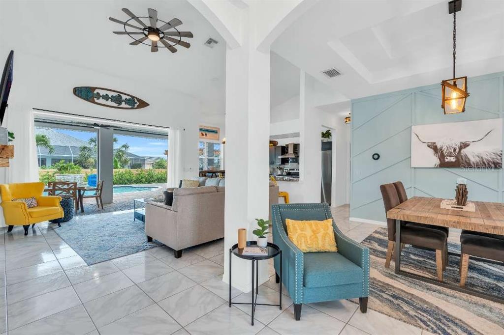 An open-concept living and dining area features tile floors, a pool view, and blue accents — 1720 SW 49TH LANE, CAPE CORAL, FL