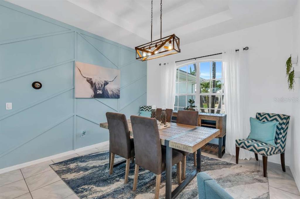 A dining room features a blue accent wall with geometric molding and a wooden table — 1720 SW 49TH LANE, CAPE CORAL, FL