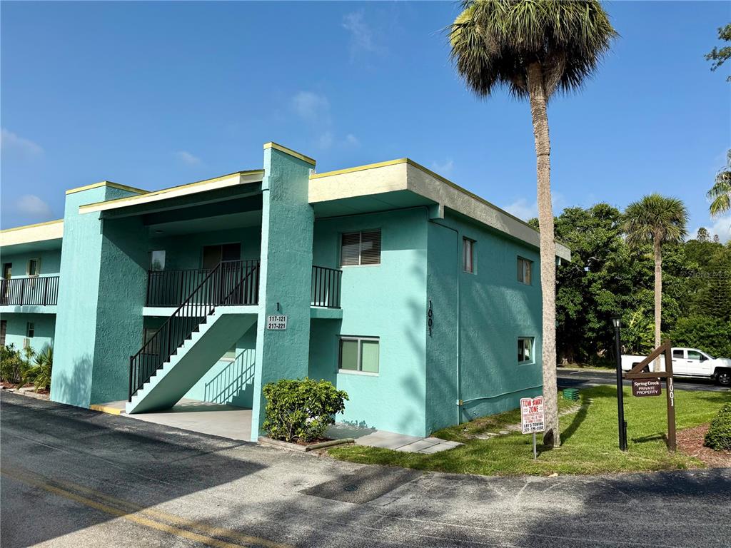 A two-story teal apartment building features an exterior staircase and a palm tree nearby — 1001 W EAU GALLIE BOULEVARD UNIT 217, MELBOURNE, FL