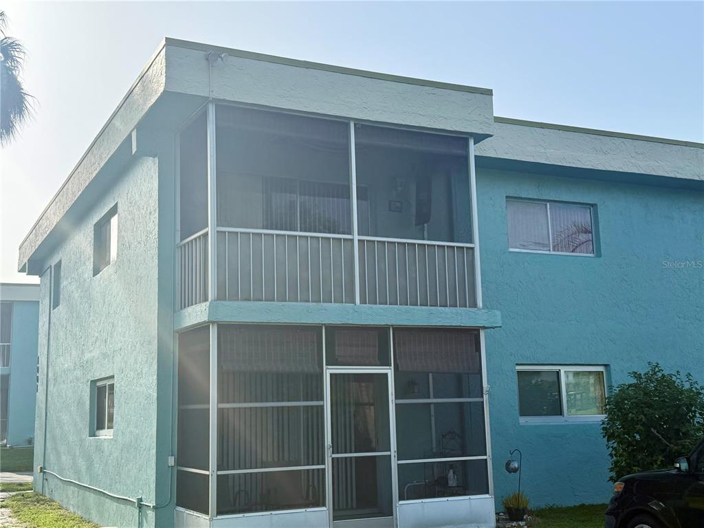 A two-story blue apartment building features stacked screened-in balconies and white-framed windows — 1001 W EAU GALLIE BOULEVARD UNIT 217, MELBOURNE, FL