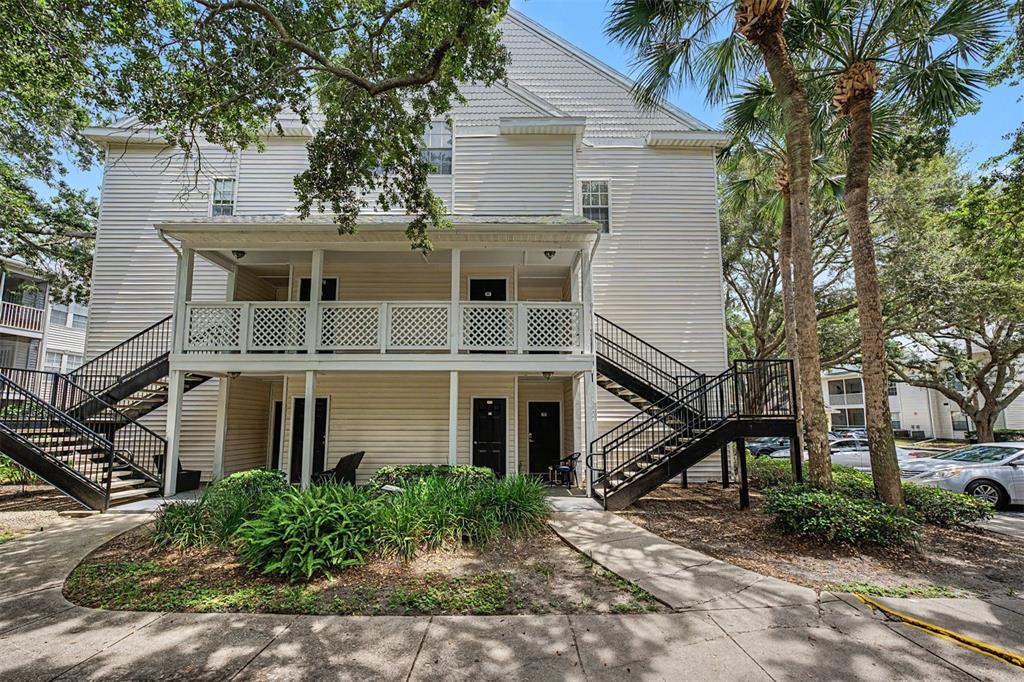 A two-story apartment building with exterior staircases, a covered balcony, and surrounding landscaping — 3270 HAVILAND COURT UNIT 301, PALM HARBOR, FL
