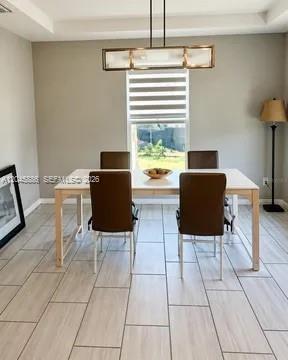 A dining room features a light wood table, four brown chairs, and a modern pendant light — 2123 NE 6th Ave, Cape Coral FL 33909, CAPE CORAL, FL